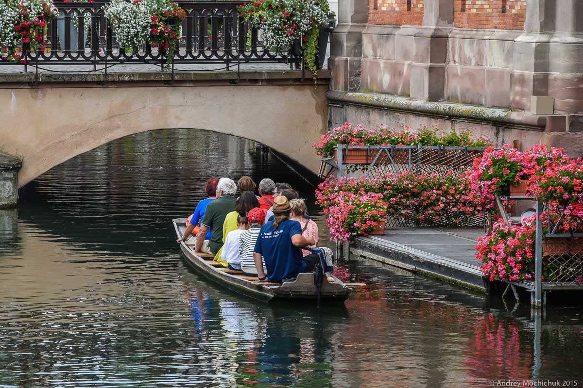 Туристы плывут в лодке по каналу в Кольмаре